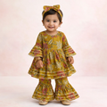 Child wearing a yellow floral outfit with a matching headband on a light pink background